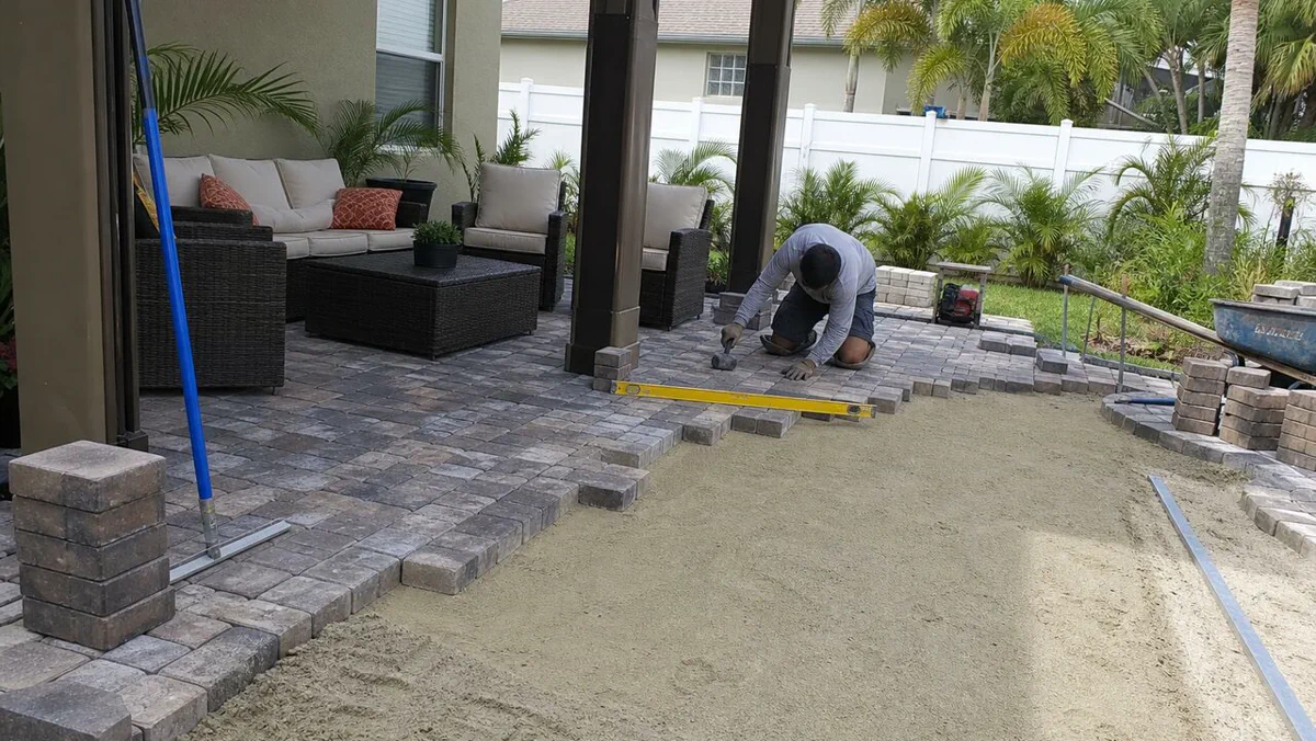 Backyard patio paver installation with base preparation and leveling tools